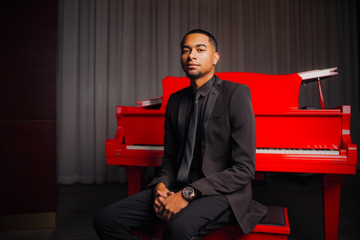 young man sitting at a red piano