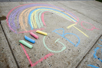 A chalk rainbow on a Mason sidewalk is shown with the multicolored letters LGBTQ underneath